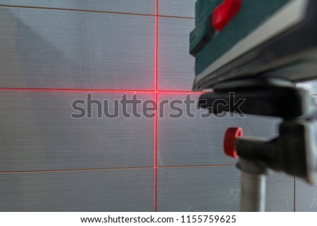 Installation of new tiles on the wall using a laser level