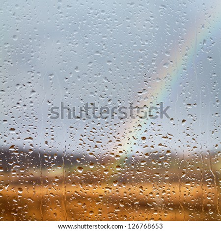 Rainbow through rained window with droplets
