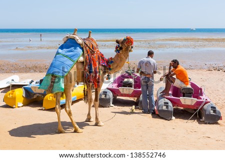 HURGHADA , EGYPT - APR 7: Unidentified native man with his camel offering ride on the beach of Hurghada on 7 April 2013. Camel ride is main tourist attraction on holidays in Egypt.