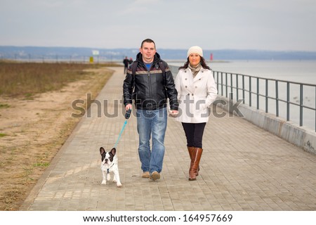Couple on the walk with dog at the sea