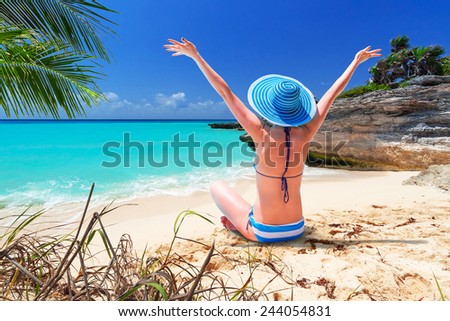 Woman in hat enjoying sun holidays on the beach of Mexico