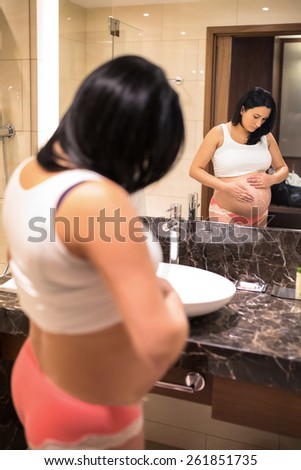 Pregnant woman in bathroom spread on anti stretch marks cream