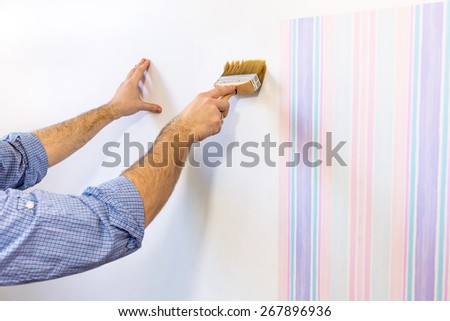 Handyman painting wall with background glue for a wallpaper