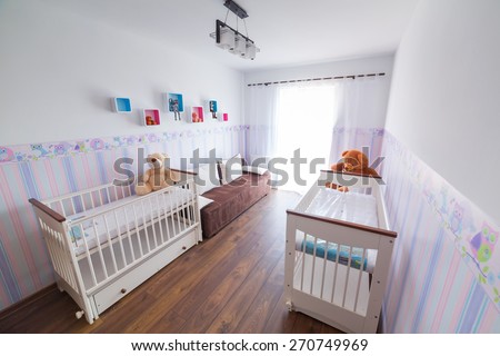 Bright baby room with pastel wallpapers and white cradles