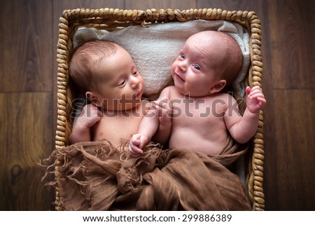 Newborn twins lying down inside the wicker basket