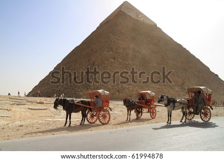 PYRAMIDS OF GIZA, EGYPT - MARCH 11: Unidentified Egyptian people offer horse ride under Great pyramids of Giza waiting for tourists March 11, 2010 in Egypt