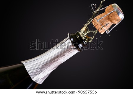 Bottle of champagne with splashes over black background