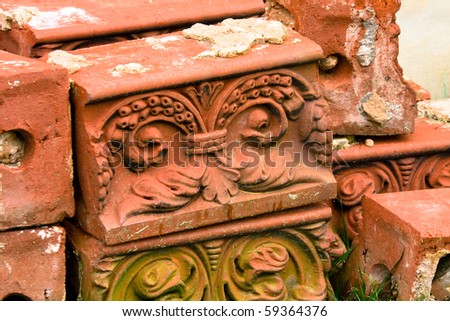 Antique decorative molded bricks salvaged from  demolished building stacked on grass.