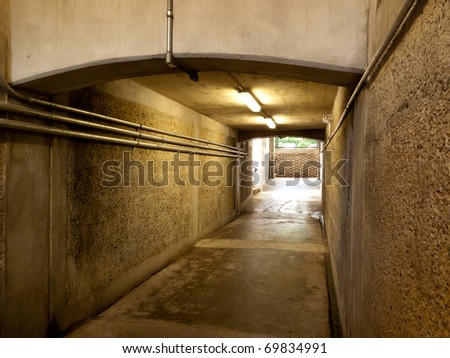 Grungy underground cement pedestrian walkway with fluorescentt lighting.
