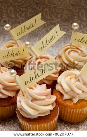 Six cupcakes with small party banners and pearl toothpicks.