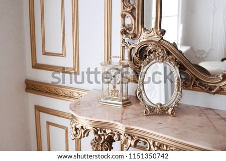luxury mirror in gold frame. mirror on a vintage dressing table. Victorian-style. mechanic clock