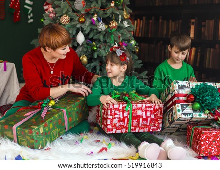 Mother with her happy kids have got gift boxes under Christmas tree