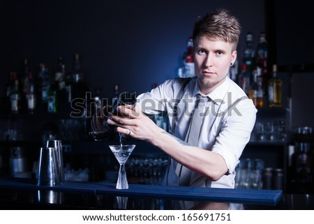 Bartender bartender is pouring a drink and looking at the camera