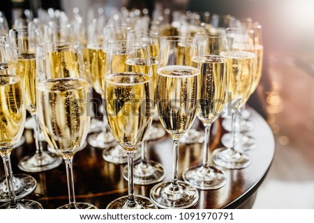 Bottle of sparkling wine with three flute glasses with bubbles floating up on gray backgrounds