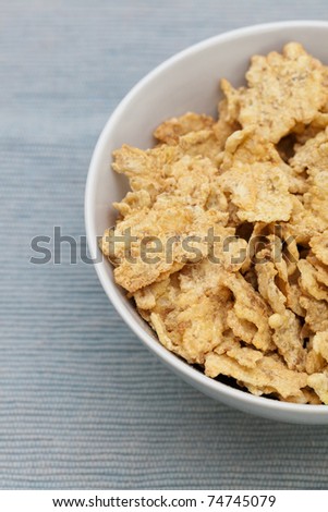 A closeup of a white bowl of cereal on a blue tablecloth.