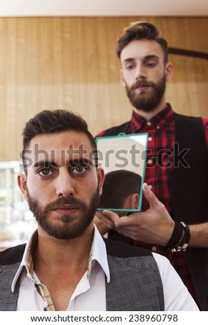 young hipster barber shows haircut to a customer