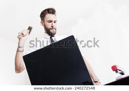 young businessman strikes hammered laptop computer