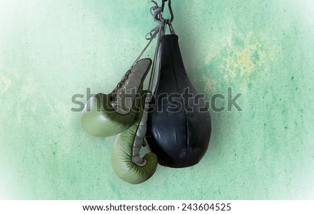 old boxing gloves and punching bag hang on hook on texture wall with copy space