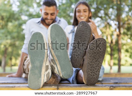 young couple in love in the park with his feet foreground