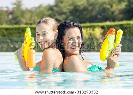 pretty girls playing with water guns in pool