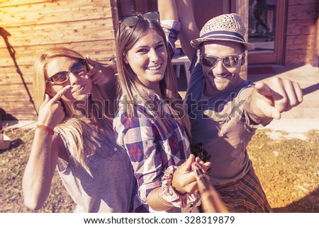 group of smiling friends taking selfie with smart phone on a warm vintage colored filtered look