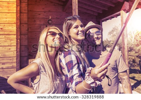 group of smiling friends taking funny selfie with smart phone on a vintage warm color filtered look