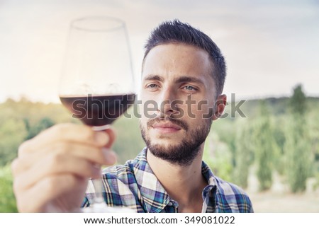 handsome bearded man looking glass of wine before drinking