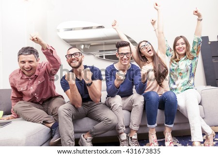 group of friends watching a football match on tv on the couch