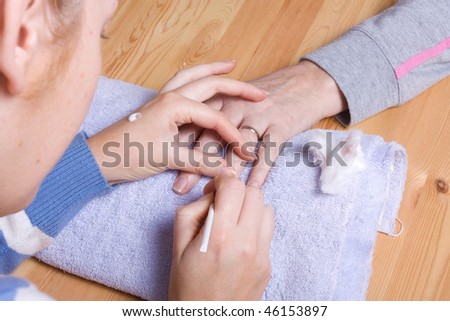 Older senior woman with arthritic hands receiving home spa treatment / manicure.