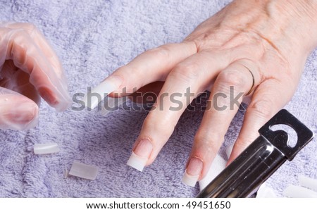 Older senior woman's hand receiving home spa/beauty treatment of nail extensions.