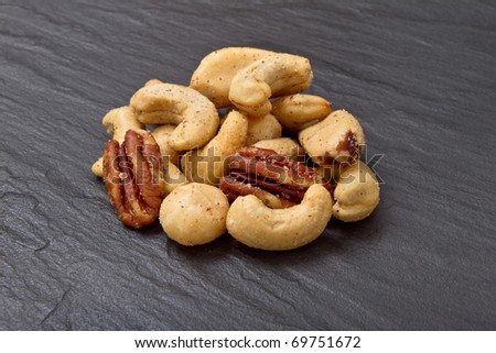 Mixed Salted Nuts from low perspective on dark grey slate background.