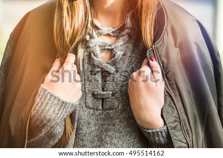 fall fashion outfit detail. woman in an autumn fashion outfit, stylish bomber jacket and grey wool sweater. warm instagram grade