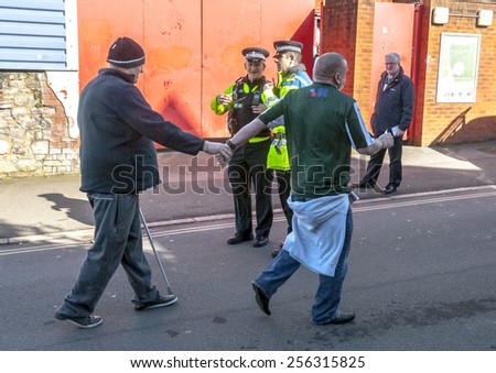 EXETER, ENGLAND - FEBRUARY 21, 2015: Plymouth Argyle supporter leads a disabled man into the football  at the League 2 football match between Exeter City FC and Plymouth Argyle FC