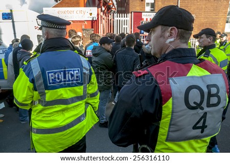 EXETER, ENGLAND - FEBRUARY 21, 2015: Devon and Cornwall Police watch Plymouth  football fans during the police operation at the League 2 football match between Exeter City FC and Plymouth Argyle FC