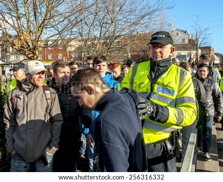 EXETER, ENGLAND - FEBRUARY 21, 2015: Police officer pushes a Plymouth Argyle football fan during the police operation at the League 2 football match between Exeter City FC and Plymouth Argyle FC