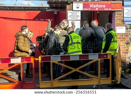 EXETER, ENGLAND - FEBRUARY 21, 2015: Security guards search Plymouth Argyle football fans during the police operation at the League 2 football match between Exeter City FC and Plymouth Argyle FC