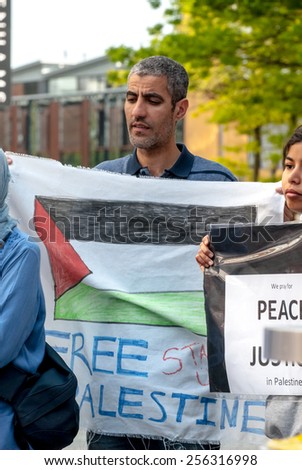EXETER, ENGLAND - JULY 15, 2014: Man hold a Free Palestine flag during the Peace Vigil for Gaza in Exeter\'s Princesshay Square.
