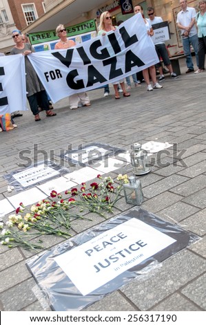 EXETER, ENGLAND - JULY 15, 2014: Peace signs, flowers and some of the peace campaigners during the Peace Vigil for Gaza in Exeter\'s Princesshay Square.