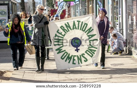 EXETER, ENGLAND - MARCH 7, 2015: International Women\'s Day banner leads the march during the Walk for Peace through the city of Exeter to celebrate International Women\'s Day.