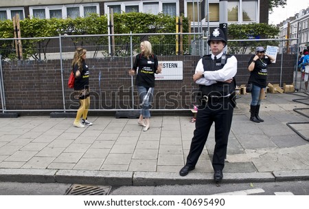LONDON - AUGUST 25:  Policeman standing, while two young women are dancing behind him during the Notting Hill Carnival on August 25, 2008 in London, England.