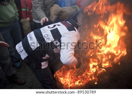 OTTERY ST MARY -  NOVEMBER 5: A young roller attempts to pick up a burning tar barrel at the start of the 2011 Tar Barrels of Ottery Carnival on  November 5, 2011 in Ottery St Mary