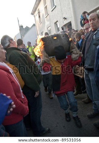 OTTERY ST MARY -  NOVEMBER 5:   young unidentified barrel roller runs through the streets of Ottery St Mary with a burning barrel at the 2011 Tar Barrels of Ottery Carnival on  November 5, 2011 in Ottery St Mary