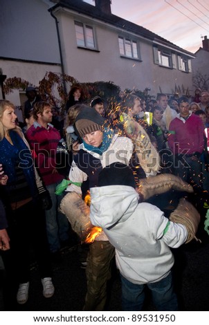 OTTERY ST MARY -  NOVEMBER 5: An unidentified barrel roller avoid the burning embers, while another attempts to extinguish his gloves at the 2011 Tar Barrels, Ottery Carnival on  November 5, 2011 in Ottery St Mary
