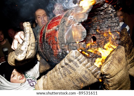 OTTERY ST MARY -  NOVEMBER 5: Gloves are burning as a young roller is helped during a burning barrel exchange at the 2011 Tar Barrels of Ottery Carnival on  November 5, 2011 in Ottery St Mary