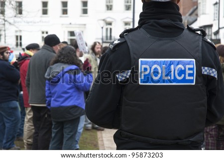 EXETER - FEBRUARY 11: A Devon & Corwall policeman watches the Occupy Exeter activists as they celebrate their achievments during leaving the green event in Exeter  on February 11, 2012 in Exeter, UK