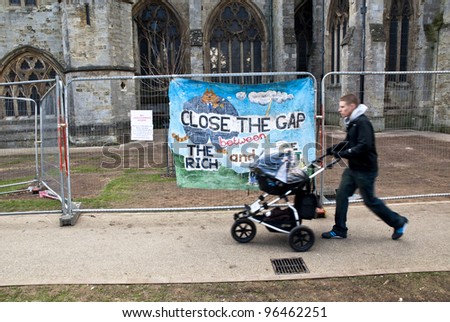 EXETER - FEBRUARY 11: A man with a baby buggy walks past a banner saying \