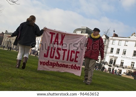 EXETER - FEBRUARY 11: Occupy Exeter activist hold up a Tax Justice banner on Exeter Cathedral green during the Occupy Exeter leaving the Exeter Cathedral Green event in Exeter.
