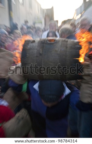 OTTERY - NOVEMBER 5: A young barrel roller runs through the crowd with a burning barrel at the 2011 Tar Barrels of Ottery Carnival  on November 5, 2011 in Ottery St Mary, UK..