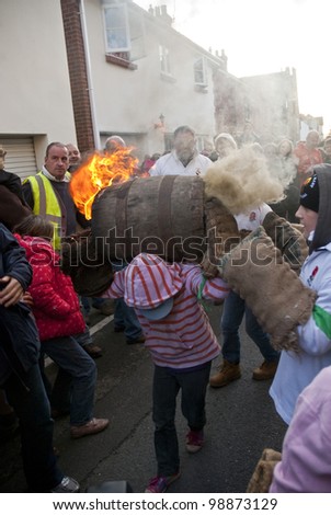 OTTERY - NOVEMBER 5: A young barrel roller runs through the crowd with a burning barrel at the 2011 Tar Barrels of Ottery Carnival  on November 5, 2011 in Ottery St Mary, UK.
