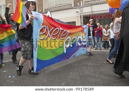 EXETER - MARCH 31: Festival goers hold up the Exeter Pride banner at the Exeter Pride 2012 Parade in Exeter City centre  on March 31, 2012 in Exeter, UK